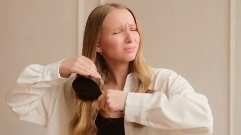 Young woman has problems with combing brushing her dry damaged hair Stock Footage 151326617