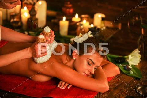 Young woman have hot poultice massage in spa salon. Stock Photos