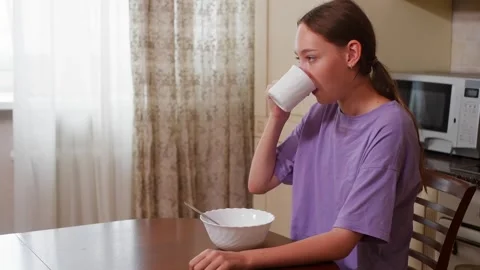 Young woman having breakfast at kitchen table Stock Footage 344716216