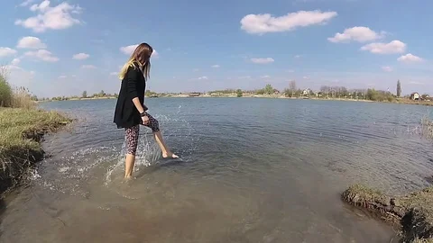 Young woman is having fun,and splashing water surface with foot Stock Footage