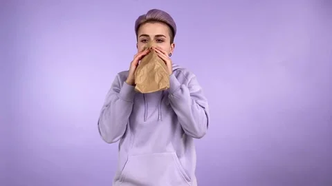 Young woman having panic attack, breathing using paper bag isolated Stock Footage 197956397