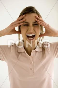 Young woman with head in hands, shouting, close-up Stock Photos