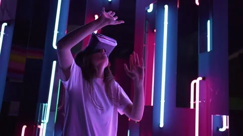 A young woman in headset is explore VR. Neon light. A joyful new experience in Stock Footage 145193371