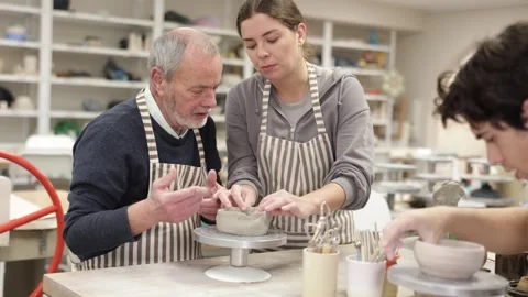 Young woman helping eldery man sculpting ceramic piece Stock Footage 344848031