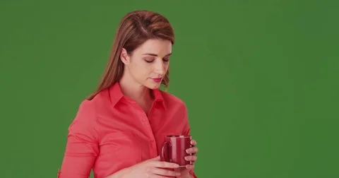 Young woman in her 20s drinking a cup of coffee on green screen Stock Footage