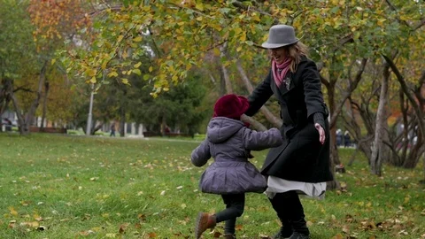 A young woman with her daughter is walking in the park, Mom is a child Stock Footage