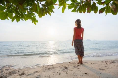 Young woman in hippie pants enjoys solitude on the sandy tropical beach Stock Photos