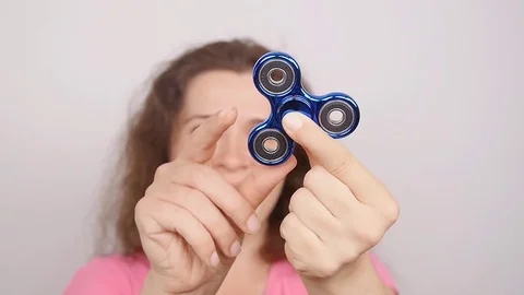 Young woman holding and playing with fidget spinner. studio shot on white Stock Footage