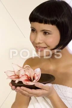 Young woman holding bowl with orchid blossoms, portrait Stock Photos