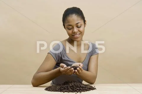 A young woman holding coffee beans Stock Photos