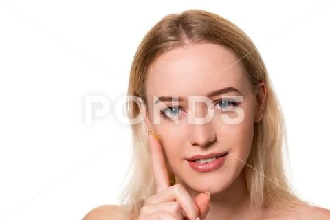 Young woman holding contact lens on index finger with copy space. Close up face Stock Photos