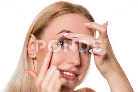 Young woman holding contact lens on index finger with copy space. Close up face Stock Photos