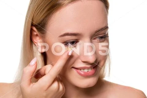 Young woman holding contact lens on index finger with copy space. Close up face Stock Photos