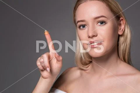 Young woman holding contact lens on index finger with copy space. Close up face Stock Photos