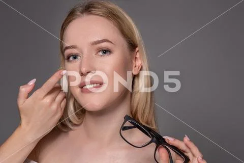 Young woman holding contact lens on index finger with copy space. Close up face Stock Photos