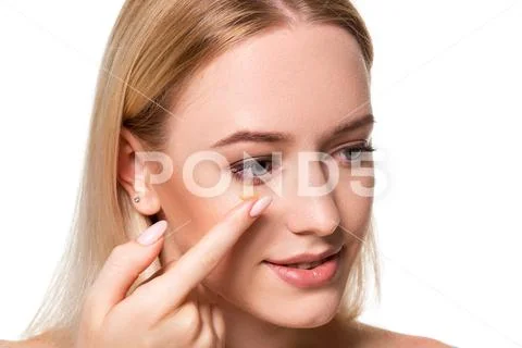 Young woman holding contact lens on index finger with copy space. Close up face Stock Photos