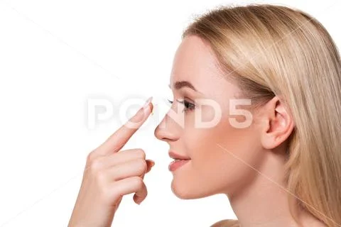 Young woman holding contact lens on index finger with copy space. Close up face Stock Photos