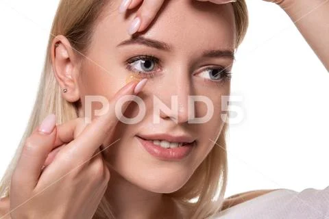 Young woman holding contact lens on index finger with copy space. Close up face Stock Photos