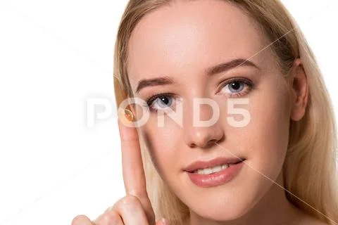 Young woman holding contact lens on index finger with copy space. Close up face Stock Photos
