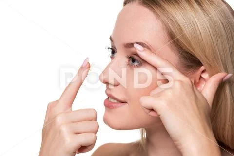 Young woman holding contact lens on index finger with copy space. Close up face Stock Photos