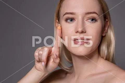 Young woman holding contact lens on index finger with copy space. Close up face Stock Photos