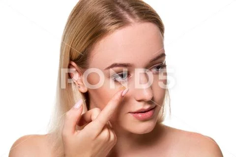 Young woman holding contact lens on index finger with copy space. Close up face Stock Photos