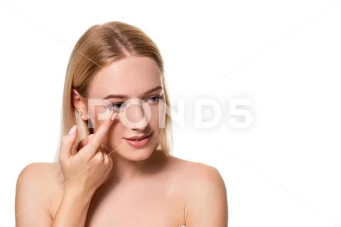 Young woman holding contact lens on index finger with copy space. Close up face Stock Photos