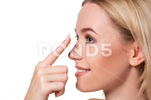 Young woman holding contact lens on index finger with copy space. Close up face Stock Photos
