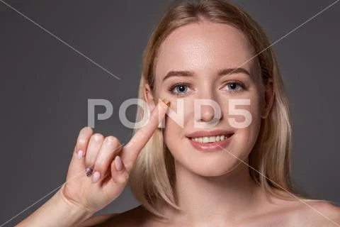 Young woman holding contact lens on index finger with copy space. Close up face Stock Photos