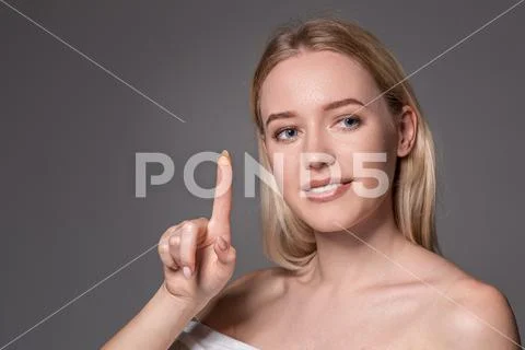 Young woman holding contact lens on index finger with copy space. Close up face Stock Photos
