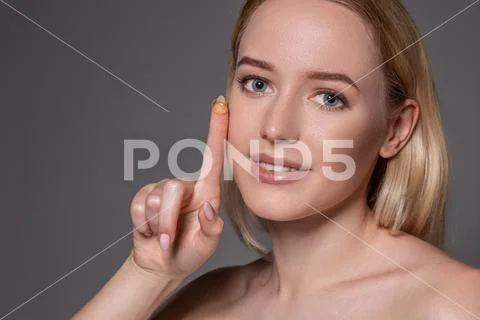 Young woman holding contact lens on index finger with copy space. Close up face Stock Photos