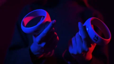 A young woman holding controllers while wearing VR glasses, Red and blue Stock Footage 221129881