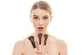The young woman holding cosmetic brushes on the white background Photo