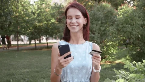 Young woman holding a credit card and using cell phone for online shopping. Stock Footage