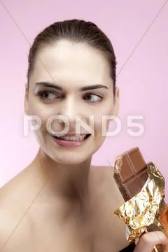A young woman holding a large chocolate bar looking guilty Stock Photos