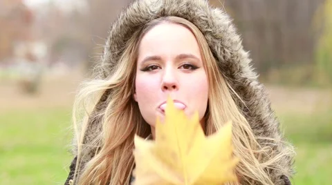 Young woman holding leaf in front of the face, moving it and making funny faces Stock Footage 59554411
