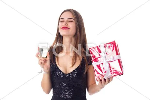 Young woman holding a present and a glass of champagne Stock Photos