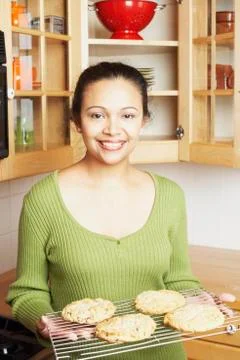 Young woman holding a rack of baked goods Stock Photos