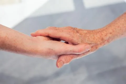 Young woman holding senior woman hands, close-up. Tender gesture between two  Stock Photos