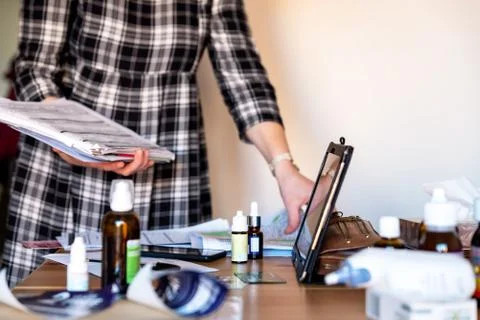 Young woman holding stack of documents over table with medicines at new home Photos