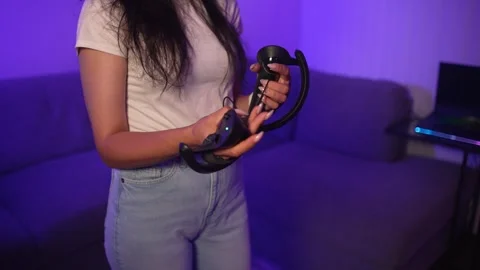 Young woman holding VR controllers preparing for virtual reality gaming at home Stock Footage 333725317