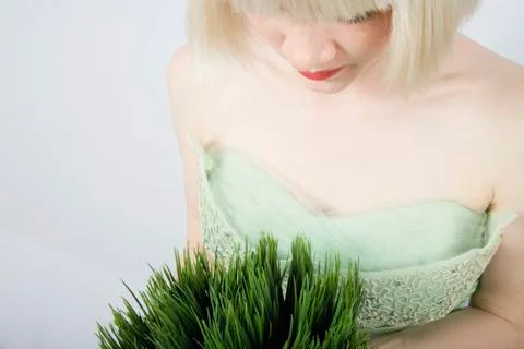 A young woman holding a wheatgrass plant Stock Photos