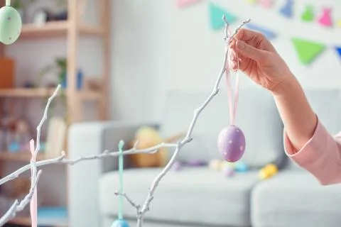 Young woman at home easter celebration concept hanging egg on tree Stock Photos