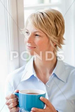 Young Woman At Home Holding Cup