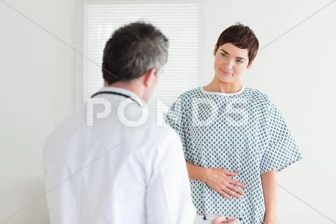 Young Woman in hospital gown talking to her doctor Stock Photos