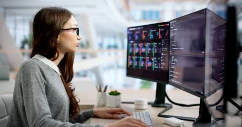 Young Woman Intensely Typing Code At Her Office Computer Desk. Stock Photos