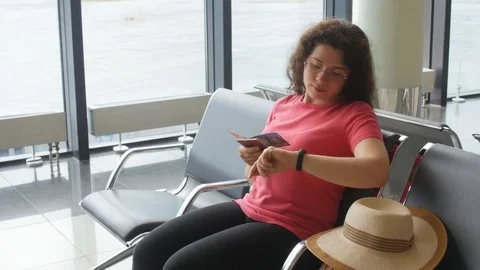 Young woman at international airport looking at smartphone and waiting her Stock Footage