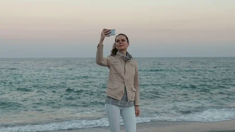 Young woman in a jacket and jeans takes pictures of herself Stock Footage
