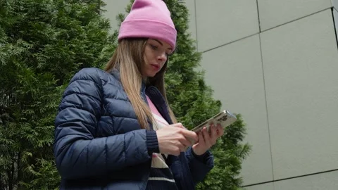 A young woman in a jacket using smartphone by thujas. Stock Footage 273015388