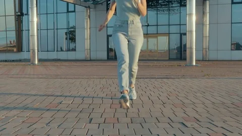 Young woman in jeans and a t-shirt happily runs towards Stock Footage